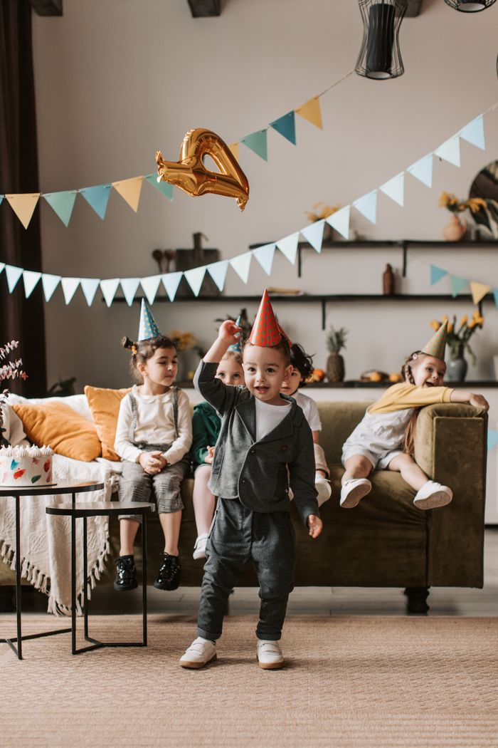 Happy children celebrating a birthday at home with balloons and decorations. Joyful indoor gathering.